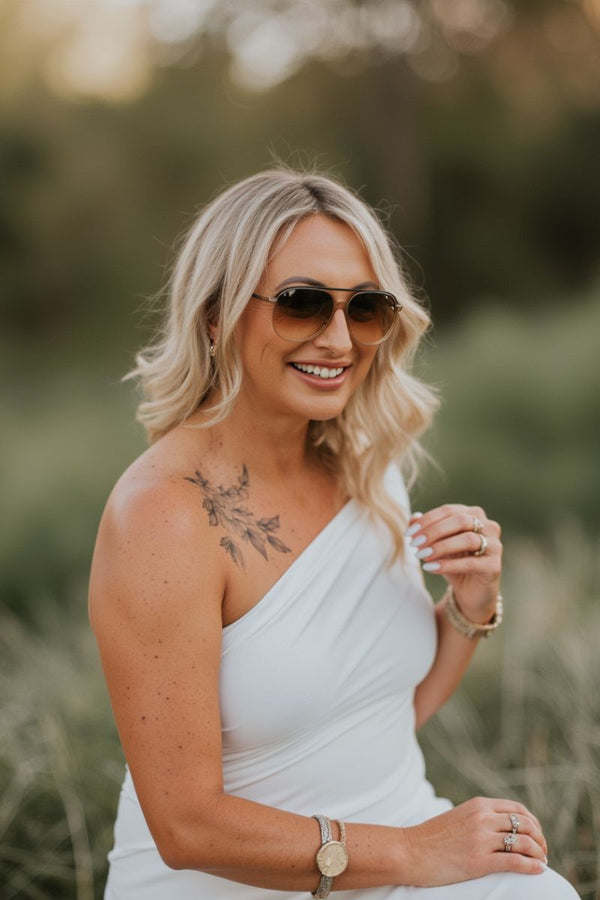 Empowerment coach Alidia smiling confidently outdoors in white dress and sunglasses — radiating strength and joy after heartbreak healing.
